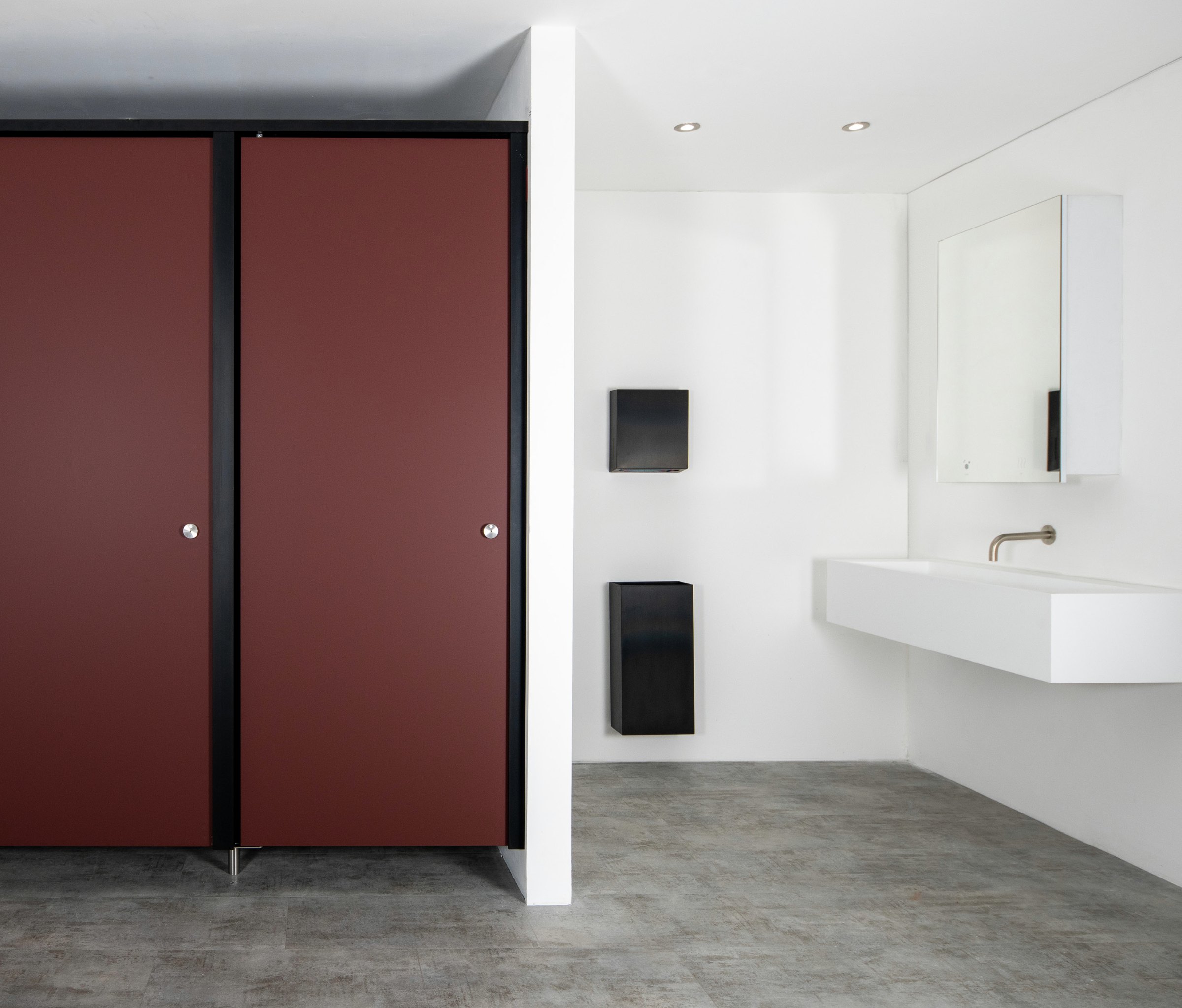 A maroon full-height cubicle door installed in a white commercial washroom